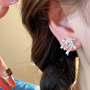 Élégantes boucles d'oreilles puces nœud en argent avec zircons portées par un modèle