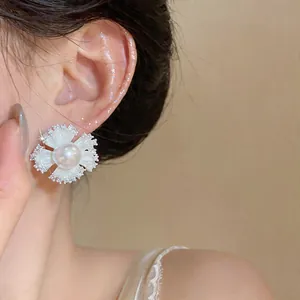 Close-up detail of a French style flower stud earring with pearl and zircon on model