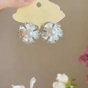 Macro view showing the intricate floral design, pearl center, and zircon stones on earrings