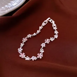 Elegant silver flower bracelet with pink zircons and pearls displayed on brown velvet fabric