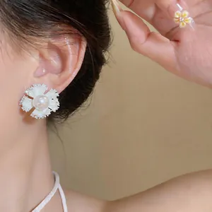 Close-up detail of a delicate white flower earring with a central pearl and zircon.