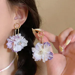 Detail view of purple fabric flower drop earrings with golden rings for vacation style