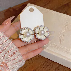 Close-up view of elegant flower-shaped earrings featuring pearls and sparkling zircons
