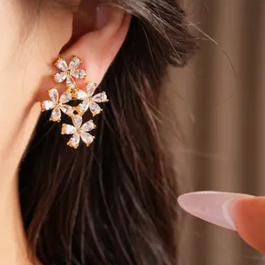 Close-up detail of exquisite 18K gold-plated flower ear clips featuring sparkling zircon