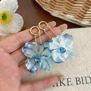 Close-up detail of blue gradient fabric flower earrings with gold metal loops.