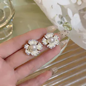 Close-up of elegant flower stud earrings with central pearl and sparkling zircons