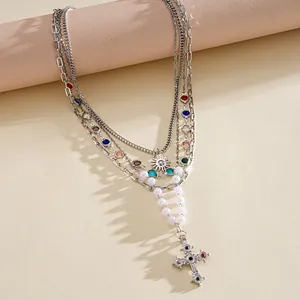 Dettaglio ravvicinato di una collana vintage a più strati con croce e perle.