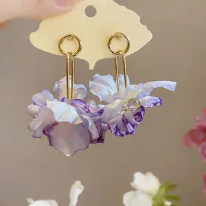 Macro view of delicate purple floral petal earrings with gold-toned metal accents