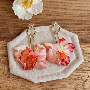 Detail view of elegant pink fabric flower earrings on a hexagonal display stand.