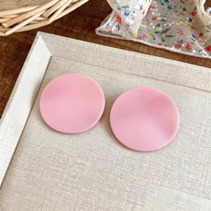 Elegant pastel pink crinkled circular stud earrings with silver needles on a textured tray display