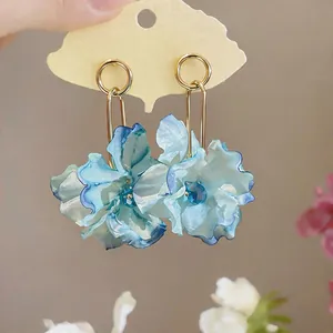 Detailed view of elegant blue fabric flower earrings with gold hoops and blue crystals