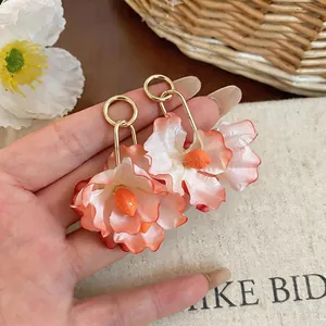 Close-up of peach gradient fabric flower earrings with gold hooks for beach vacations