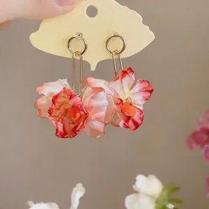 Detailed view of elegant red and pink gradient fabric flower earrings on a decorative card