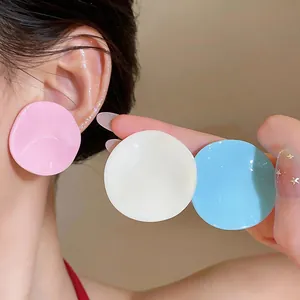 Close-up detail of colorful pleated round stud earrings in pink, white and blue
