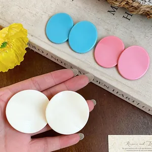 Detailed view of colorful round stud earrings in vibrant blue, pink and creamy white shades