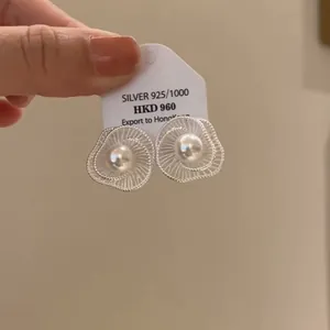 Detaillierte Nahaufnahme von eleganten hohlen Blumenohrringen in Silber mit Perle