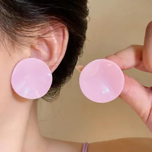 Close-up of sweet pink pleated circular stud earrings worn on ear