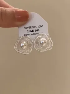 Detailansicht eleganter silberner Blumenohrstecker mit einer zentralen Perle auf weißer Karte