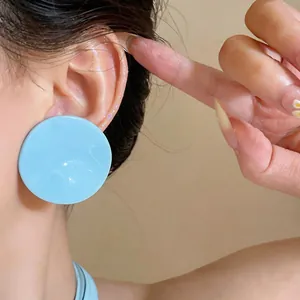 Close-up of sky blue wrinkled round stud earrings on ear for a sweet aesthetic