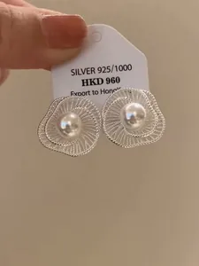 Detailansicht der silbernen Ohrstecker in hohler Blumenform mit einer Perlenmitte.