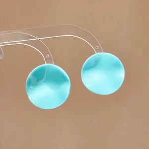 Close-up of turquoise wrinkled circular stud earrings on a transparent display stand.