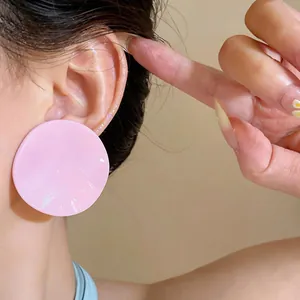 Close-up view of a sweet pink ruffled round stud earring worn on an ear for detail