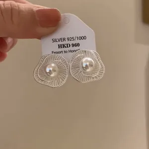 Nahaufnahme von hohlen Blumenohrringen mit weißer Perle in Silber-Finish