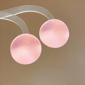 Detail of pink round pleated stud earrings with a pearl-like luster on a stand