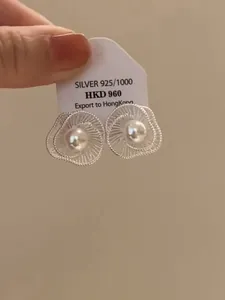 Detailansicht eleganter silberner Hohlblumen-Ohrstecker mit zentraler weißer Perle.