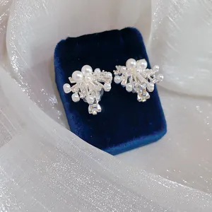 Close-up of fireworks design clip-on earrings with white pearls and zircons on velvet.