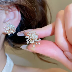 Close-up of fireworks style ear clips with pearls and sparkling zircons in gold plating.