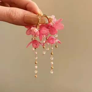 Gros plan de boucles d'oreilles fleurs en résine rose avec glands de perles