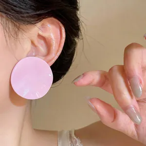 Detailed close-up view of a pink pleated round stud earring worn on an Asian model's ear