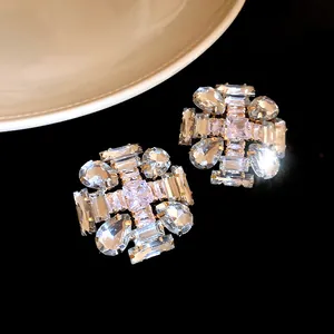 Detailed view of silver stud earrings with sparkling clear zircons in elegant cross pattern