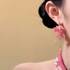 Gros plan de boucles d'oreilles en résine à fleurs roses avec de longs pompons en perles