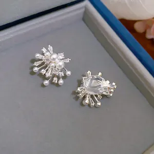 Detailed view of elegant firework clip earrings with pearls and zircons on a gray pad