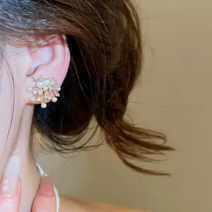 Close-up detail of 18k gold-plated zircon and pearl firework-shaped clip-on earrings.