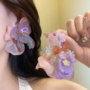 Dettaglio di orecchini a fiore in resina e chiffon con texture fini e design dolcissimo