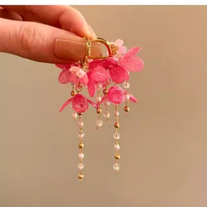 Vue détaillée de boucles d'oreilles fleur en résine rose avec longs glands de perles
