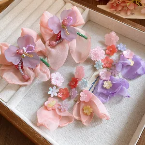 Dettaglio di orecchini a fiore in chiffon fatti a mano con perle in resina in un portagioie