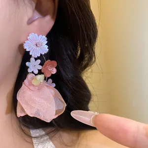 Vista dettagliata di eleganti orecchini pendenti a fiore in chiffon pesca indossati