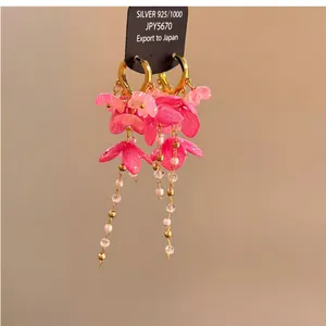 Vue macro détaillée des boucles d'oreilles fleurs en résine rose avec glands de perles
