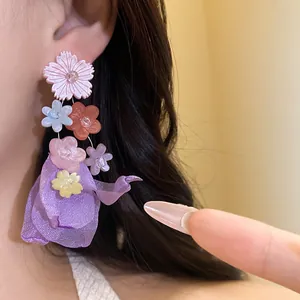 Dettaglio di un orecchino pendente con fiori colorati in resina e chiffon indossato