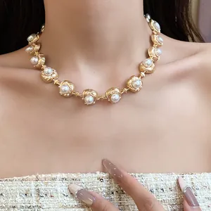 Close-up detail of a vintage gold-toned necklace with white pearls worn by a model.