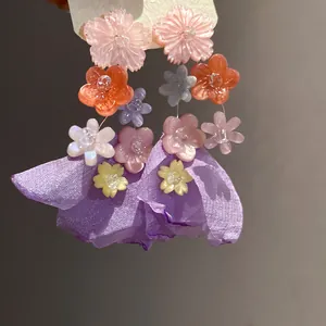 Dettaglio orecchini a fiore in chiffon e resina nei toni del viola e rosa cipria