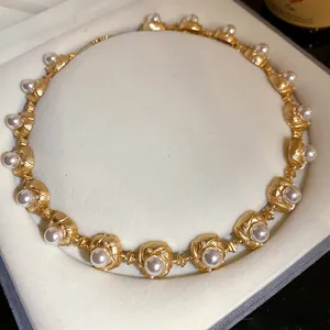 Close-up of a vintage court-style necklace featuring textured gold-tone links and pearls.