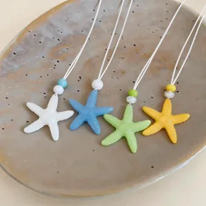 Dettaglio di collane con ciondolo a stella marina in resina blu, verde, gialla e bianca