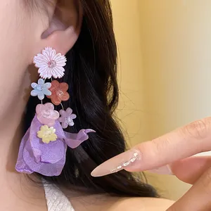 Primo piano di orecchini a pendente con fiori in chiffon e resina colorata su modella