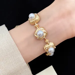 Detailed view of vintage court style matte gold bracelet with white pearls worn on wrist