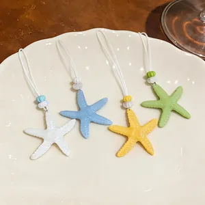 Dettaglio di ciondoli a forma di stella marina in resina in quattro colori estivi su un piatto